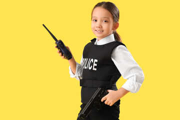 Cute little police officer with radio transmitter and gun on yellow background. Opposite Day...