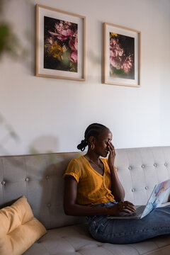 Woman making facepalm gesture and smiling while using laptop