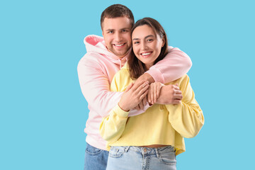 Happy young couple hugging on blue background