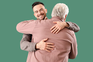 Young man with his father hugging on green background