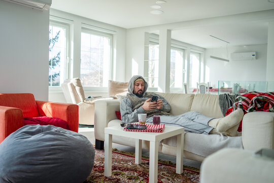 Ill Man Laying on his Couch and Using his Phone 