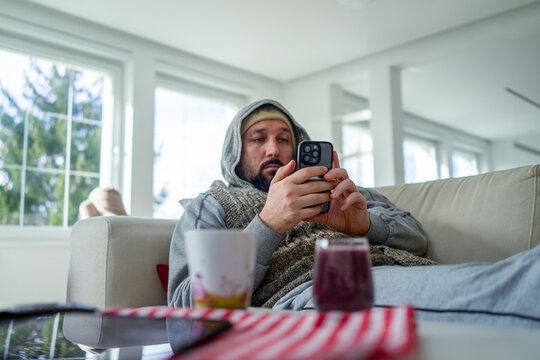 Ill Man Laying on his Couch and Using his Phone 