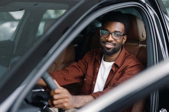 Man sitting in driver seat with hands on steering wheel of automobile
