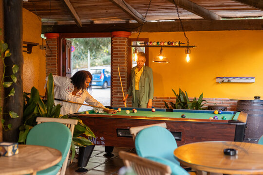 A couple plays pool in a snack bar