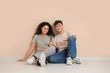 Young couple sitting on floor near beige wall in their new flat