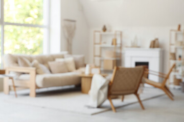 Cozy sofa, armchairs and coffee table in interior of living room. Blurred view