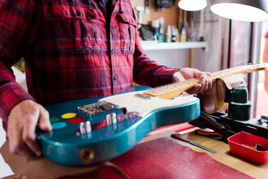 Luthier hands holding fixed electric guitar
