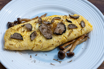 French omelette with mushrooms, fresh farmers eggs and black summer truffle mushroom in pieces for...