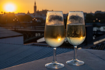 Drinking of cava or champagne sparkling wine on outdoor roof terrace with view on central part of old Sevilla, Andalusia, Spain sunset