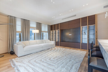 A living room in a luxury apartment with an exclusive interior design. Light carpet .by the white sofa, built-in wardrobe with shelves.
