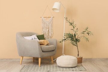 Stylish grey armchair with standard lamp and houseplant near beige wall