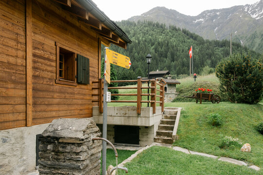 Swiss chalet with alps in background, and hike signage in front