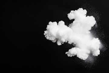 Several white dust particles splash in the air after a powder explosion on a black background.