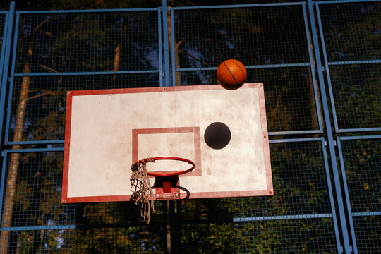 Ball flying into basketball hoop in park on sunny day