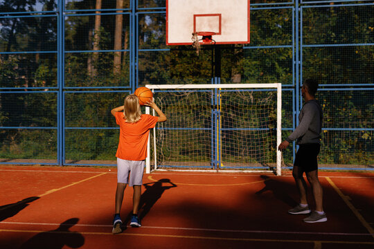 Boy making two-handed set shot under supervision of basketball coach