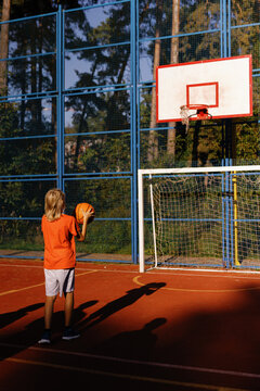 Kid performing two-handed basketball set shot on outdoor court
