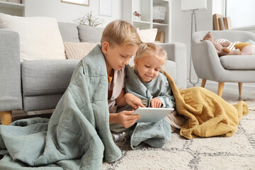 Little boy and girl with plaids using tablet at home