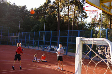 Pupil making basketball jump shot under supervision of PE teacher