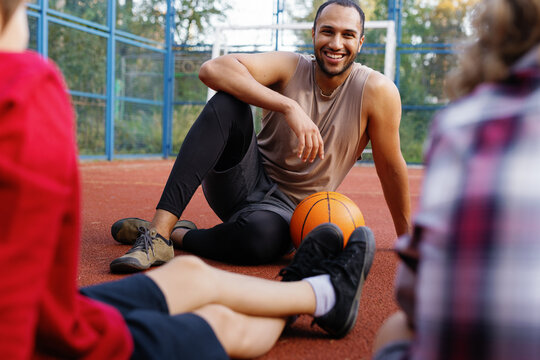 Trainer communicating with students resting after basketball game