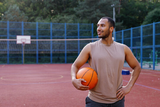 Smiling PE teacher standing alone on basketball court and looking away