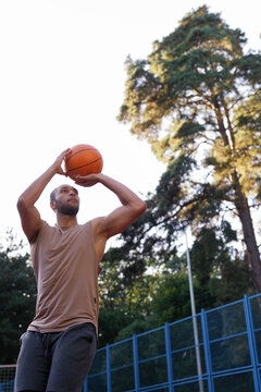 Basketball player standing on outdoor court and making set shot