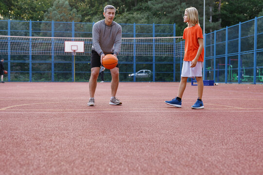 Personal trainer teaching student to make set shot on basketball court