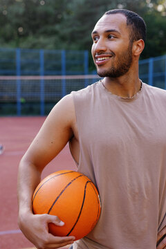 Basketball coach standing alone on outdoor court and looking away