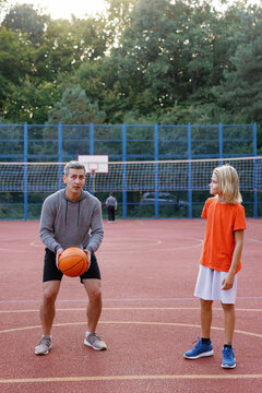 Father teaching son how to perform set shots on basketball court