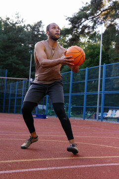 Basketball player trying to throw ball into hoop on outdoor court