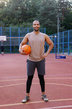 Basketball coach posing with ball in middle of outdoor court