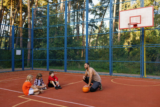 Trainer communicating with group of schoolboys during PE lesson