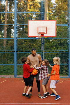 Schoolboys embracing PE teacher on court after basketball training
