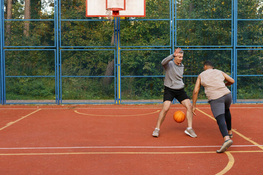Defender attempting to block opponent dribbling basketball during game
