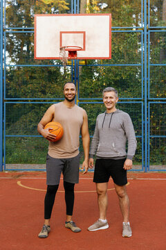 Two sporty friends posing on outdoor basketball court
