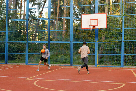 Athlete dribbling basketball on court chased by defender during game
