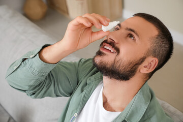 Young man applying eye drops at home
