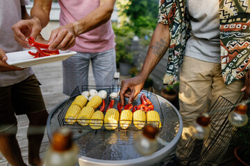 Cropped of men preparing vegetables for grilling on iron net at table