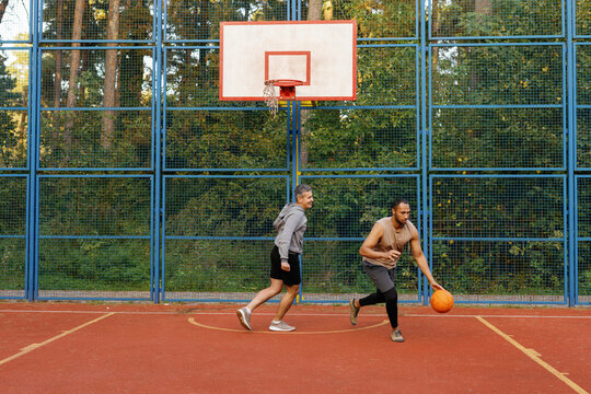 Basketball player dribbling ball on court chased by his opponent