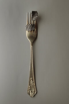 Antique silver fork with elegant earrings on a neutral background