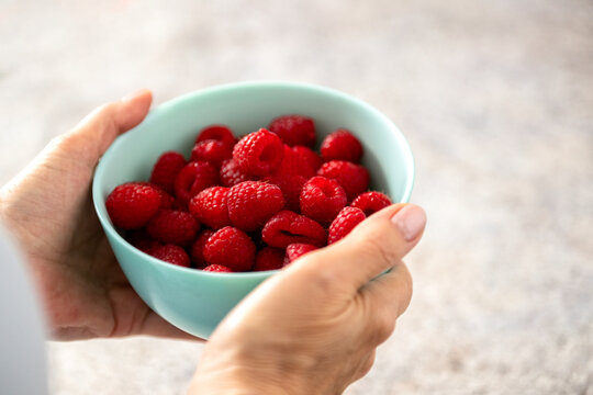 Woman holding bowl of fresh raspberries