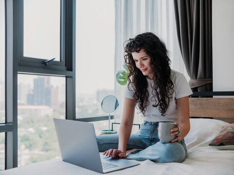 Young Woman Working From Home in Bedroom with Laptop