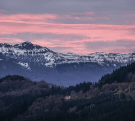House in the forest surrounded by mountains at nightfall
