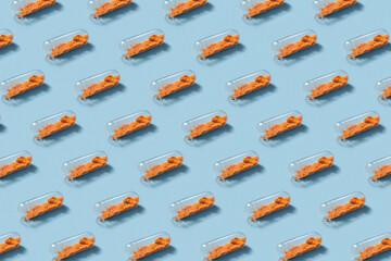 Pills with orange content placed in chess order over studio background