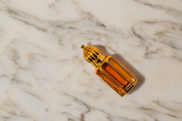 Arabian oud perfume in mini gold bottle. white marble background. Copy space.	