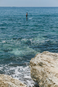 A man standing on the sup and rawing in the sea