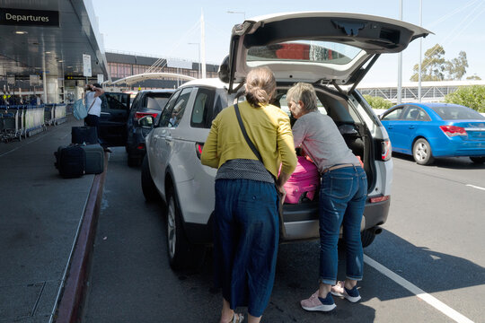 Traveler's unloading luggage at airport drop off zone
