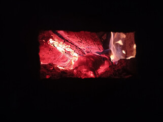 Wood burning in the dark, a small fire . Gas and wood burning stoves in the village are dangerous . Gas and wood are burned together in the stove.