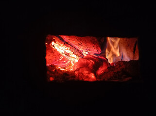Wood burning in the dark, a small fire . Gas and wood burning stoves in the village are dangerous . Gas and wood are burned together in the stove.