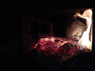 Wood burning in the dark, a small fire . Gas and wood burning stoves in the village are dangerous . Gas and wood are burned together in the stove.