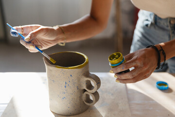 Applying Yellow Paint to Ceramic Pitcher Rim